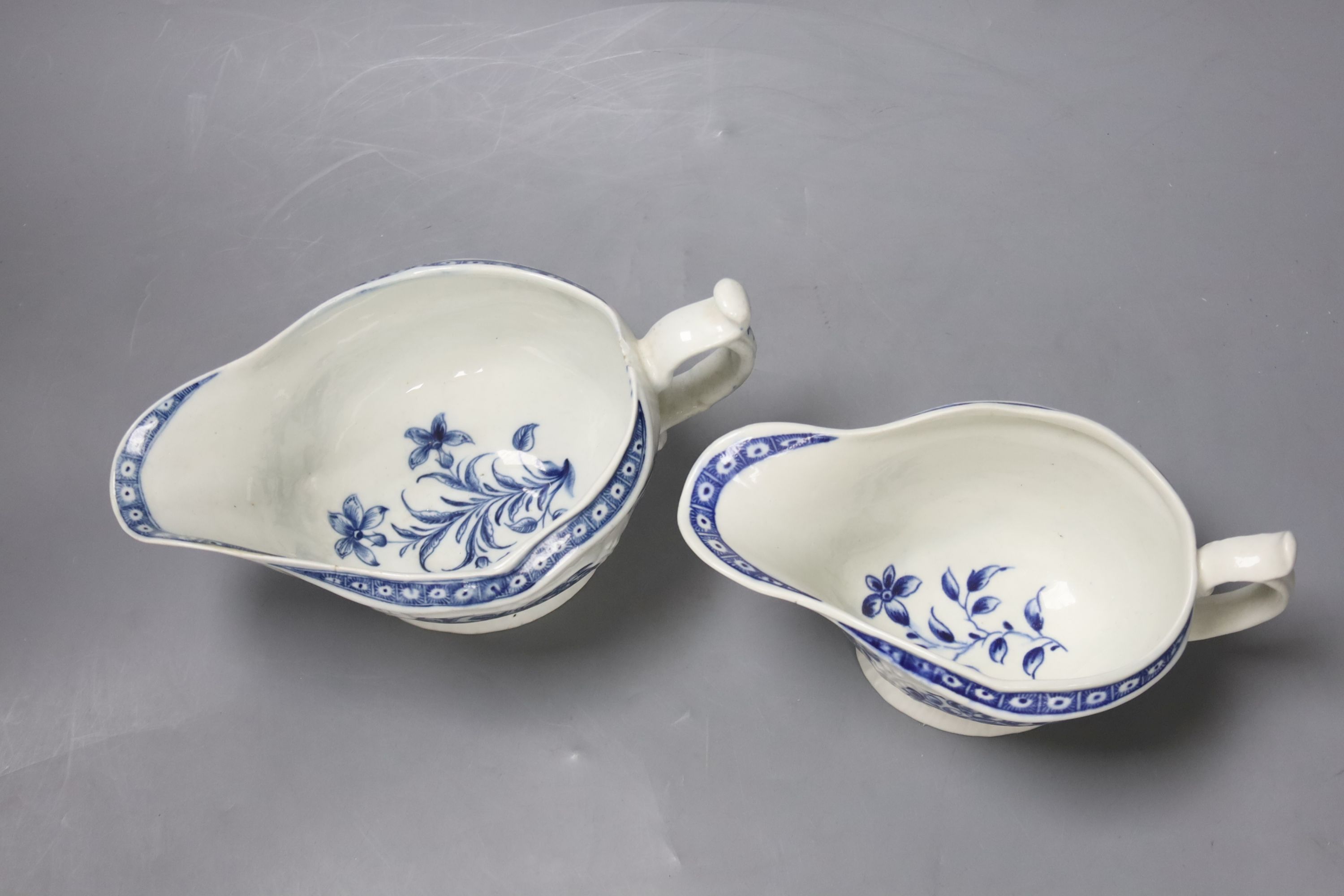 Two Worcester strap fluted floral sauceboats, c.1770, with scratch cross mark and crescent mark and the other crescent mark, height 17cm